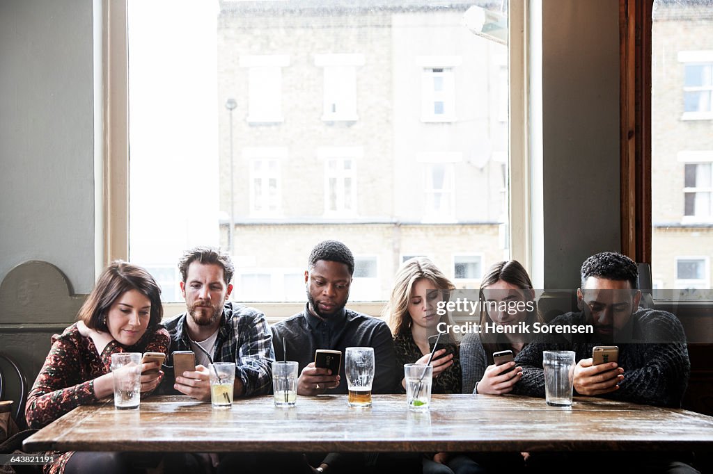 6 friends at a pub with phones