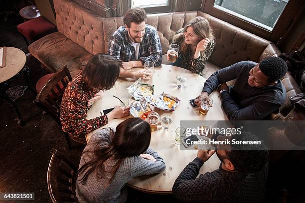 friends at a pub laughing - medium group of people stock pictures, royalty-free photos & images