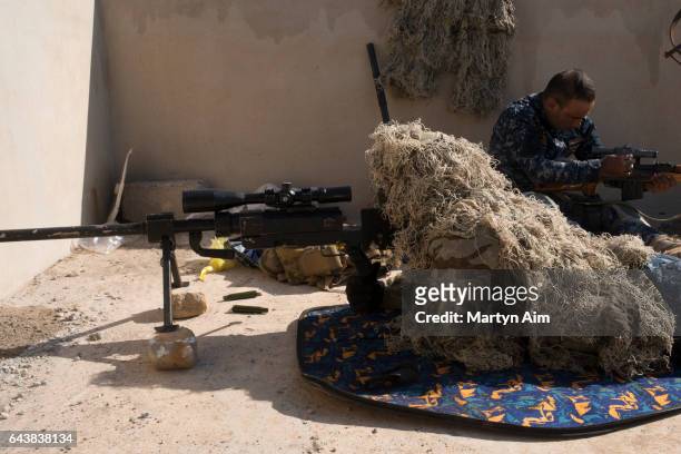 An Iraqi Federal Police sniper watches an ISIS position from the roof of a house in the Islamic State occupied village of Abu Saif, 6 kilometres from...