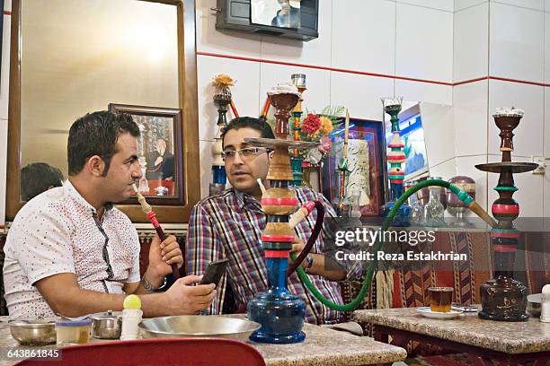 two bazaar merchants share a moment over a hookah - cachimbo narguilé imagens e fotografias de stock