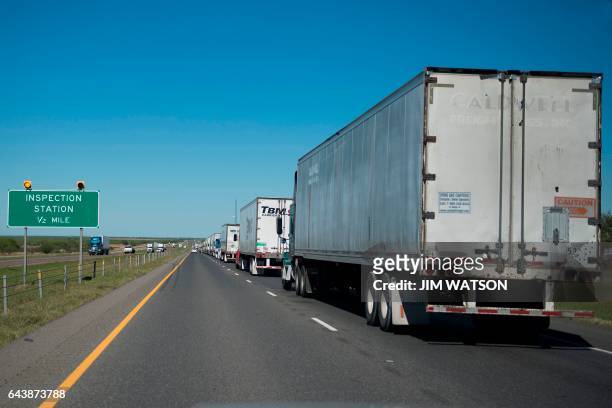 Half-mile of semi trucks line up at a US Border Patrol inspection station off the highway outside Laredo, Texas, on February 22, 2017. Attention...
