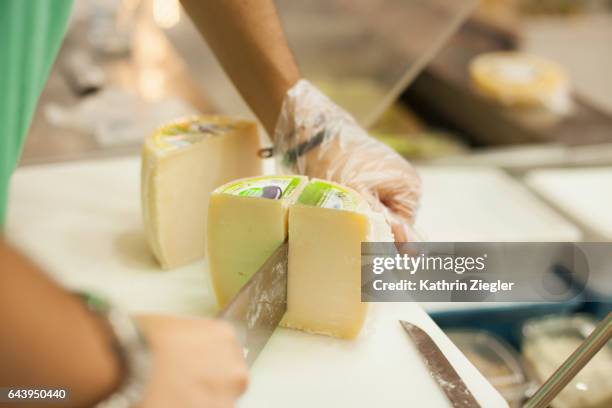 salesman at delicatessen cutting cheese, close-up of hands - cheesy salesman stock-fotos und bilder