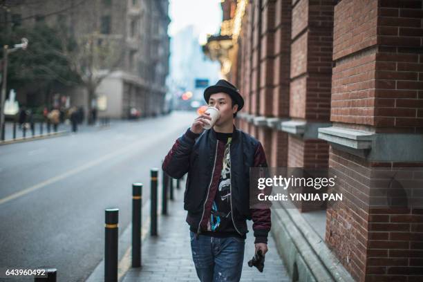 young man walking outdoors, carrying coffee cup and gloves - asian having coffee stock-fotos und bilder