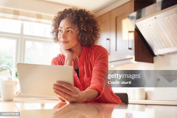 relaxing in her new kitchen with a tablet - choosing insurance stock pictures, royalty-free photos & images