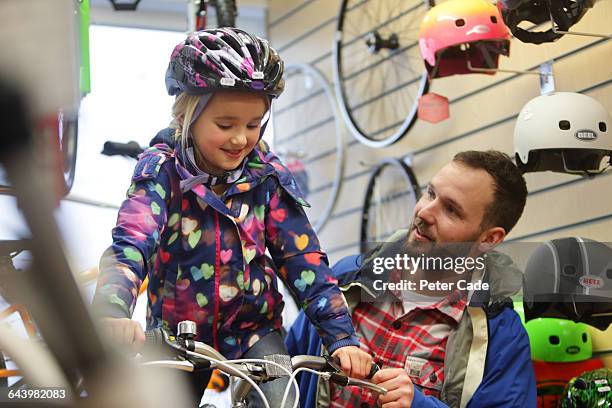 father helping daughter in bike shop - buying a bike bildbanksfoton och bilder