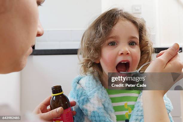 mother giving daughter medication from bottle - sick kid stock pictures, royalty-free photos & images