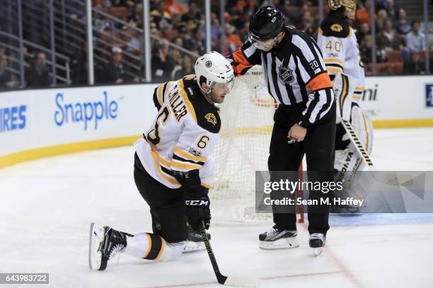 Colin Miller of the Boston Bruins gets up from the ice after being hit as referee Tim Peel helps him up during the third period of a game against the...