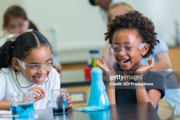 le studentesse afroamericane eccitate amano l'esperimento scientifico - scuola privata foto e immagini stock