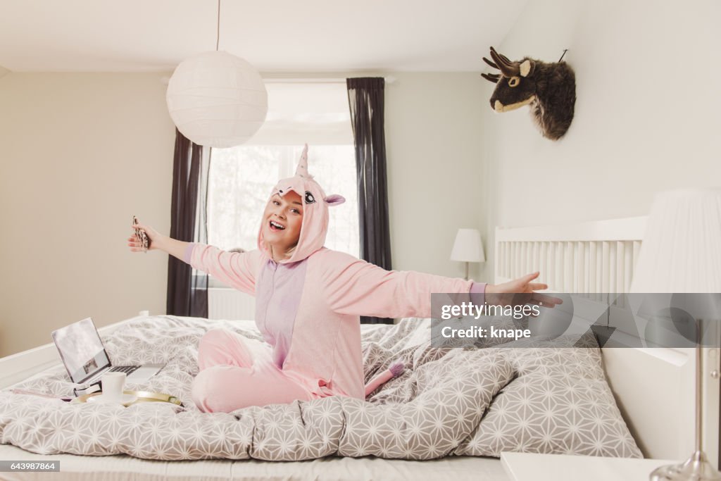 Playful woman in unicorn costume in bedroom