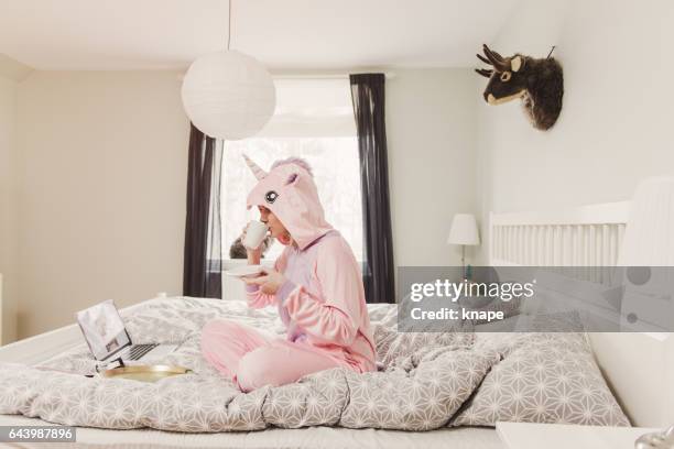 playful woman in unicorn costume in bedroom - unicorn stock pictures, royalty-free photos & images