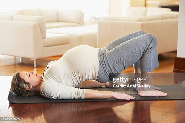 pregnant caucasian woman practicing yoga - pregnant yoga stock-fotos und bilder