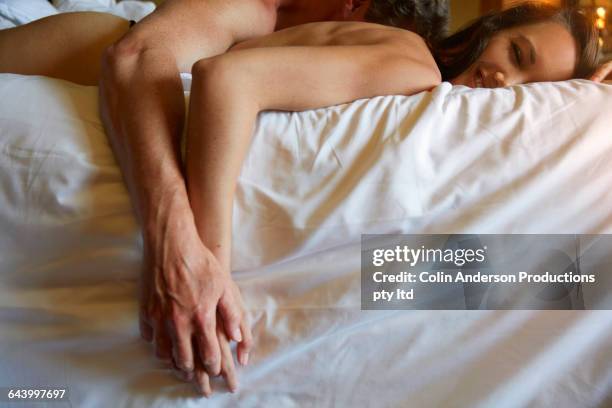 couple holding hands in bed - alluring fotografías e imágenes de stock