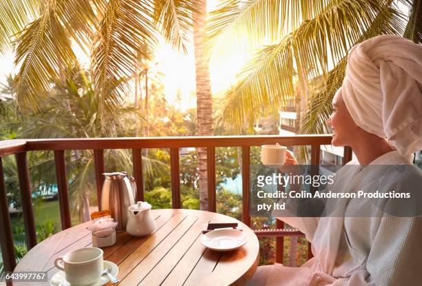 pacific islander woman drinking coffee at breakfast on balcony - ヌサデュア ストックフォトと画像