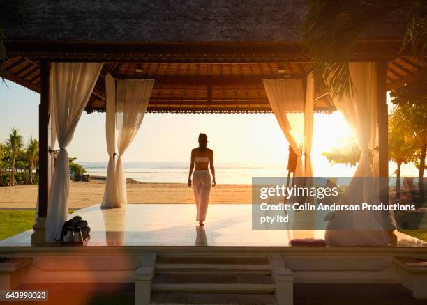 pacific islander woman in gazebo on beach - asian luxury lifestyle stockfoto's en -beelden