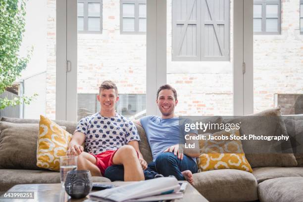 caucasian gay couple smiling on sofa - melbourne homes stock pictures, royalty-free photos & images