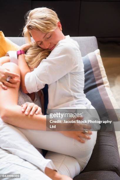caucasian lesbian couple cuddling on sofa - buttocks gay stock-fotos und bilder