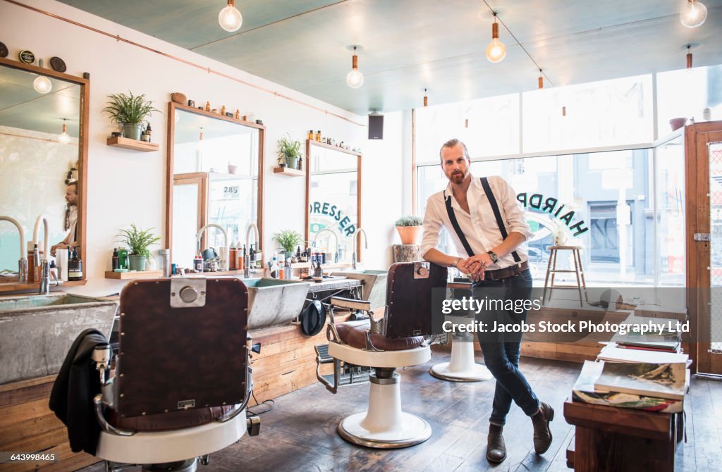 Caucasian stylist smiling in barber shop