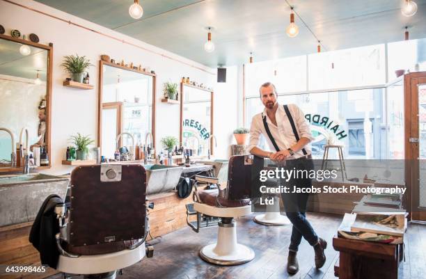 caucasian stylist smiling in barber shop - best beauty salon stock pictures, royalty-free photos & images