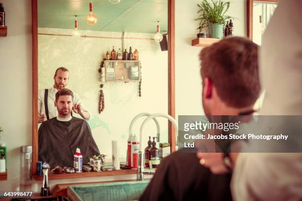 caucasian stylist cutting hair of customer in barber shop - schürze mann rückansicht stock-fotos und bilder