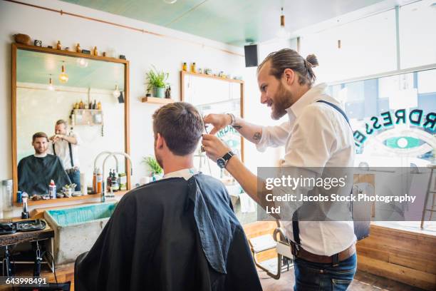 caucasian stylist cutting hair of customer in barber shop - barber stock pictures, royalty-free photos & images