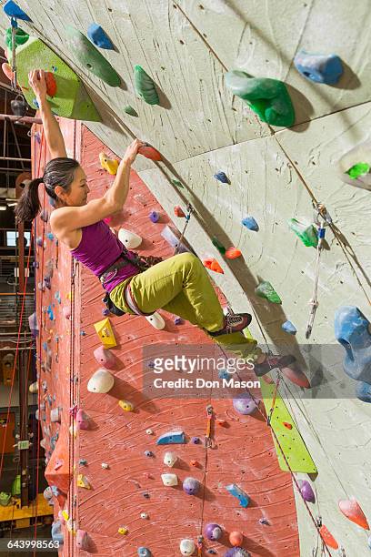 japanese woman climbing rock wall - kletterwand kletterausrüstung stock-fotos und bilder