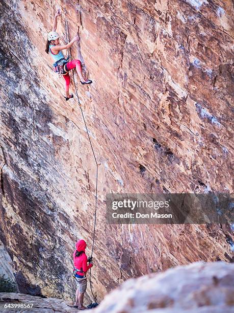 mother belaying daughter rock climbing on cliff - messa in sicurezza foto e immagini stock