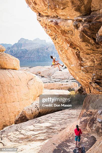 mother belaying daughter rock climbing on cliff - messa in sicurezza foto e immagini stock