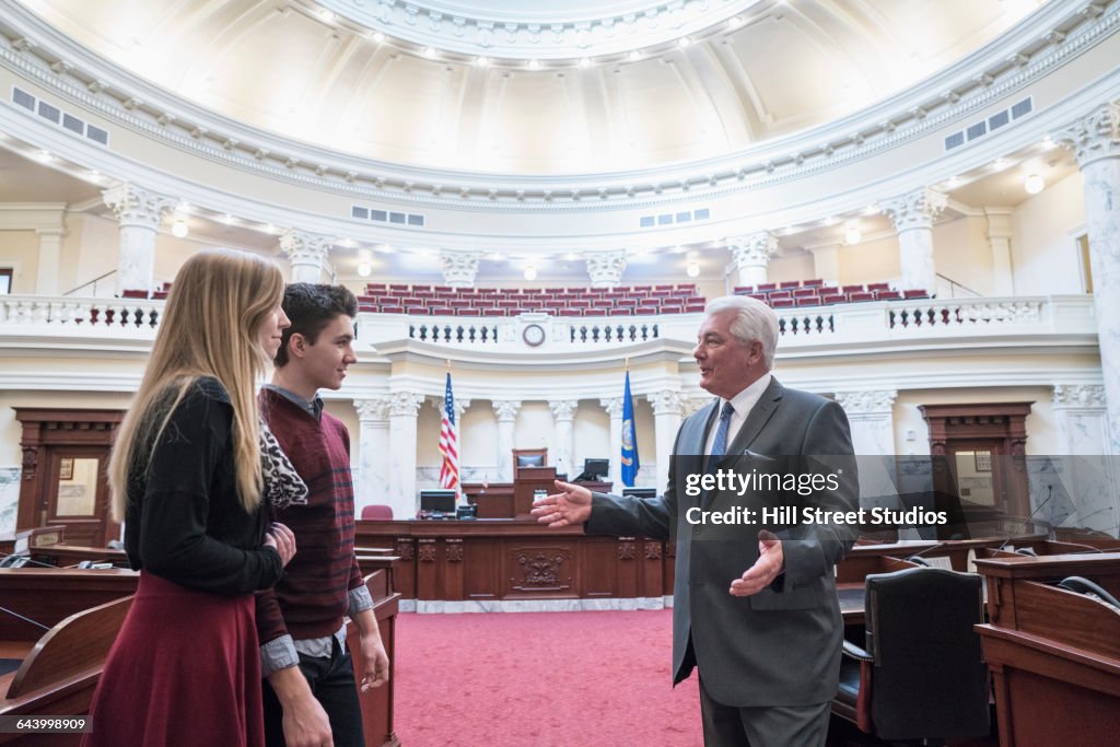Caucasian couple talking to politician in capitol building