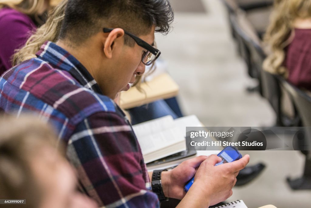 Hispanic college student using cell phone in classroom