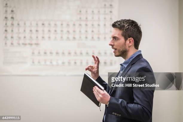 professor talking in college classroom - college student holding books stockfoto's en -beelden