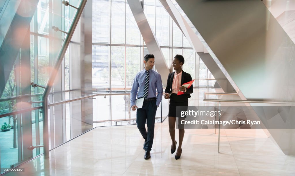 現代のオフィスロビーを歩き、話す企業のビジネスマンとビジネスウーマン
