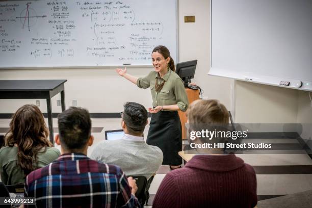 professor talking to students in college classroom - docent stockfoto's en -beelden