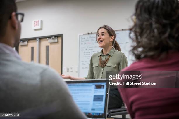 professor talking to students in college classroom - professor stock-fotos und bilder