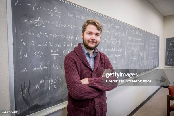 caucasian college student standing at chalkboard - mathematician photos et images de collection