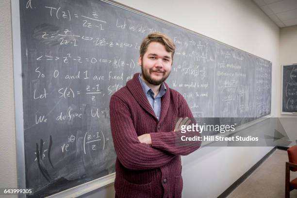 caucasian college student standing at chalkboard - mathematician stock pictures, royalty-free photos & images