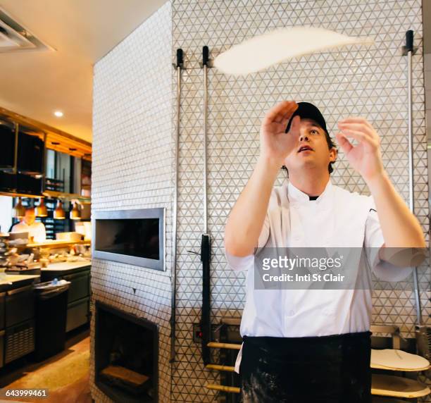 chef tossing pizza dough in restaurant in kitchen - pizza toss foto e immagini stock