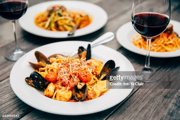 plates of seafood and pasta with wine glasses - southwest food stock pictures, royalty-free photos & images