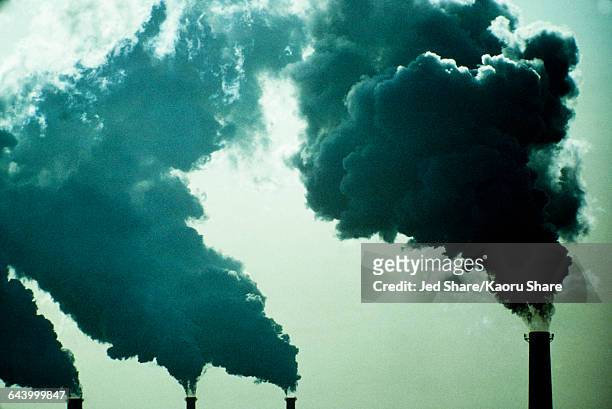 smoke billowing from industrial smoke stacks - air pollution photos et images de collection