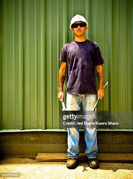 caucasian construction worker holding wrenches on work site - dirty construction worker stock pictures, royalty-free photos & images