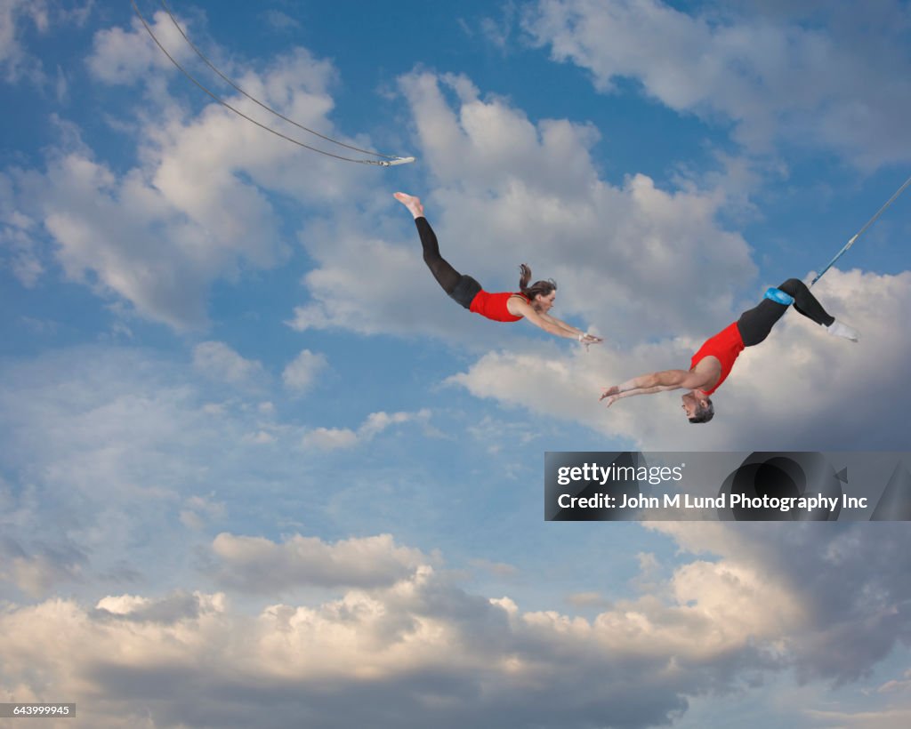 Trapeze artists jumping in sky