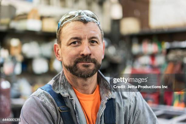 caucasian worker smiling in factory - blue collar portrait stock-fotos und bilder