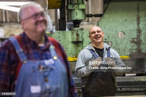 Caucasian workers laughing in factory