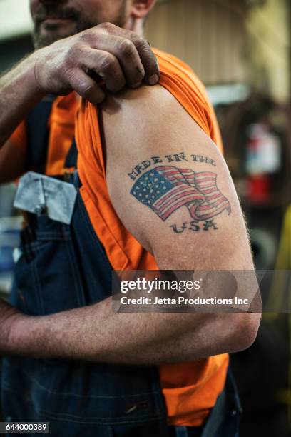 caucasian worker displaying tattoo in factory - frase breve foto e immagini stock