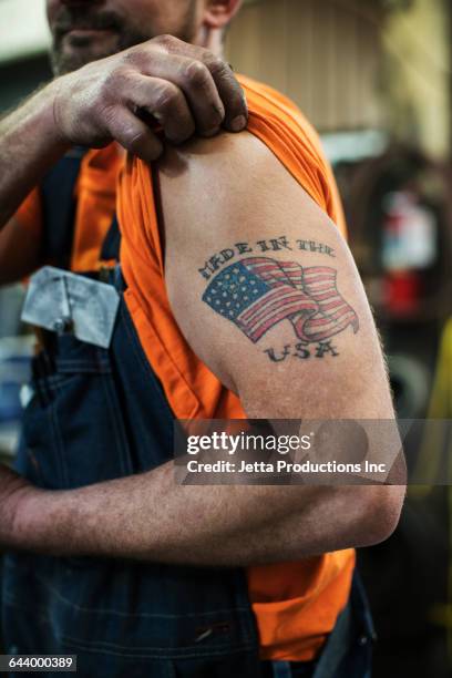 caucasian worker displaying tattoo in factory - tattoo arm stockfoto's en -beelden
