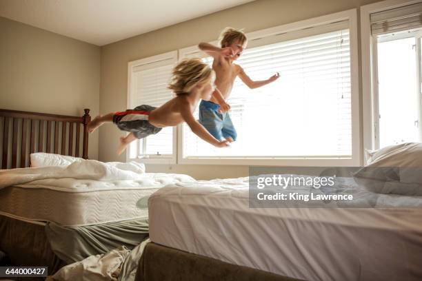 caucasian boys jumping on beds - bett machen stock-fotos und bilder