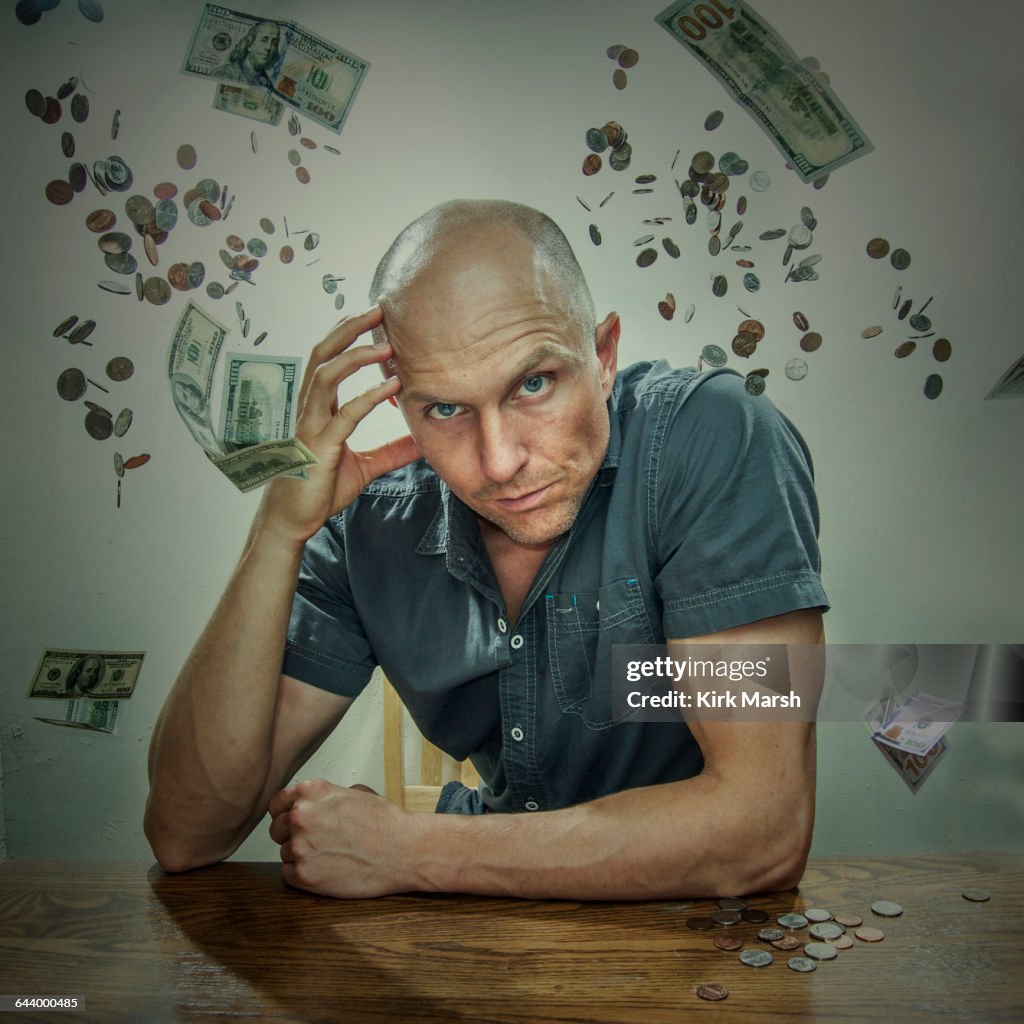 Caucasian man sitting in falling money