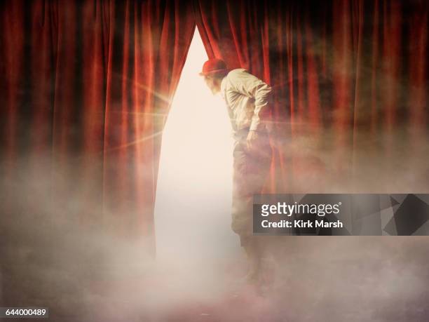 caucasian man peering through red curtain - curtain imagens e fotografias de stock