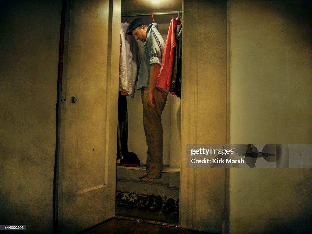 Caucasian man hanging with clothing in closet