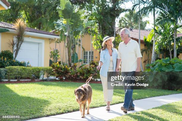 caucasian couple walking dog in neighborhood - ボカラトン ストックフォトと画像