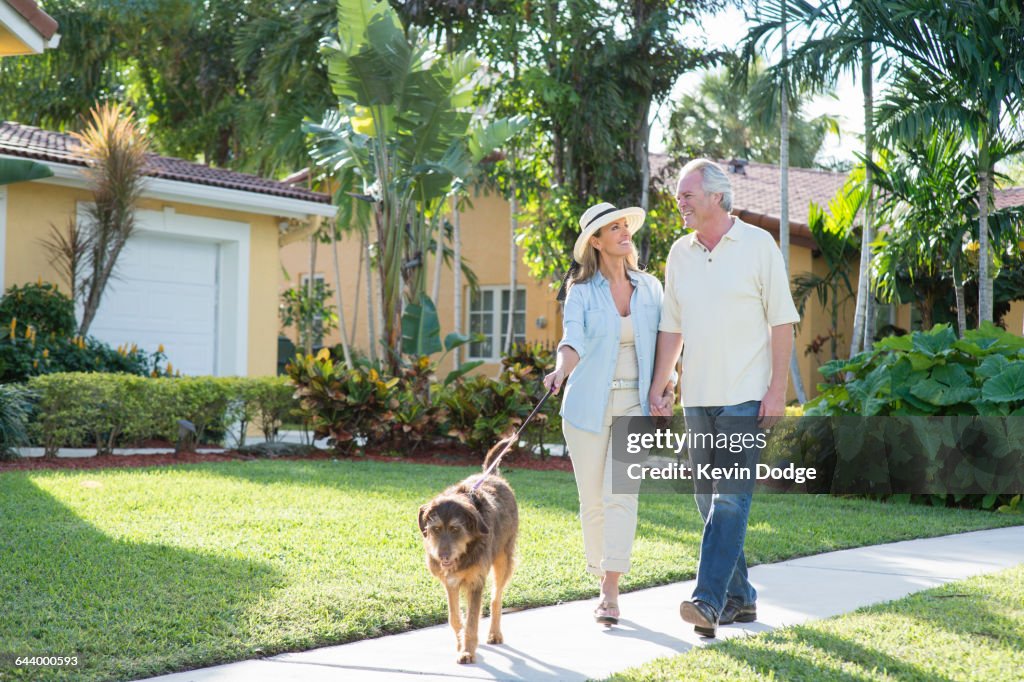 Caucasian couple walking dog in neighborhood